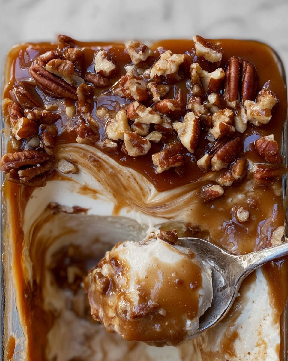 The dish is a layered dessert served in a white rectangular baking dish with handles on the sides. The bottom layer is a light creamy color with a smooth texture, topped by a thick layer of rich brown caramel sauce sprinkled generously with chopped pecans, adding a rough texture and crunch. A spoon is scooping out the dessert from the corner, revealing the creamy layer beneath the caramel. The dish is placed on a white marbled surface with slices of green and red apples beside it. Photo taken with an iphone --ar 4:5 --v 7