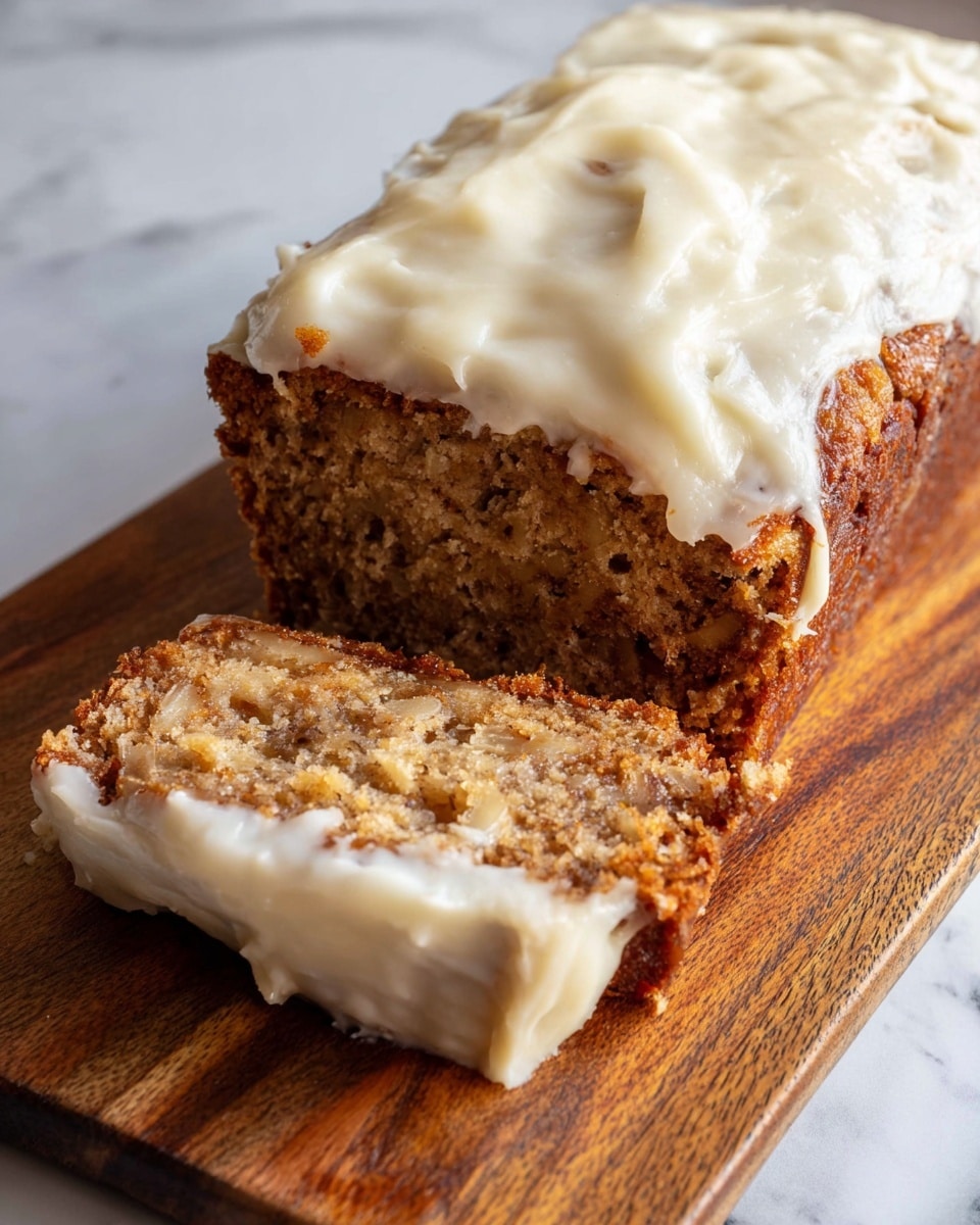 The image shows a loaf of banana bread with two layers: the bottom layer is the moist, textured banana bread in light and medium brown tones with visible bits of banana inside, and the top layer is a thick, creamy white frosting spread unevenly over the top, covering most of the surface and slightly dripping down the sides. A slice of the banana bread is cut and placed in front, showing the inside texture and some frosting on its edges. The bread rests on a wooden board over a white marbled surface. Photo taken with an iphone --ar 4:5 --v 7