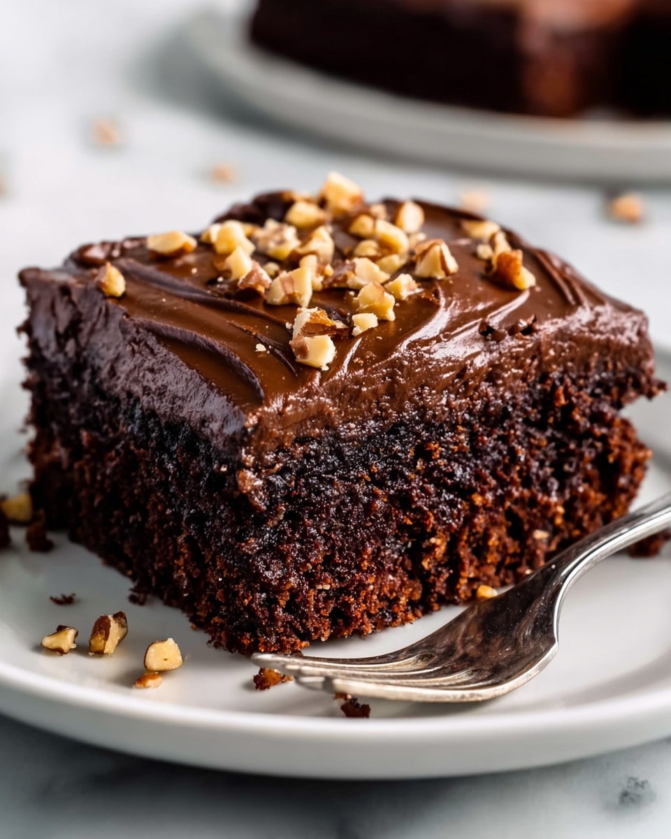 A square dark brown cake in a white pan is covered with a thick, shiny layer of smooth milk chocolate frosting that has swirled, creamy texture across the top. Scattered on the frosting are small, uneven pieces of chopped nuts adding a light brown and beige crunch contrast. The pan rests on a white marbled surface, clearly showing the entire top layer of the cake. photo taken with an iphone --ar 4:5 --v 7
