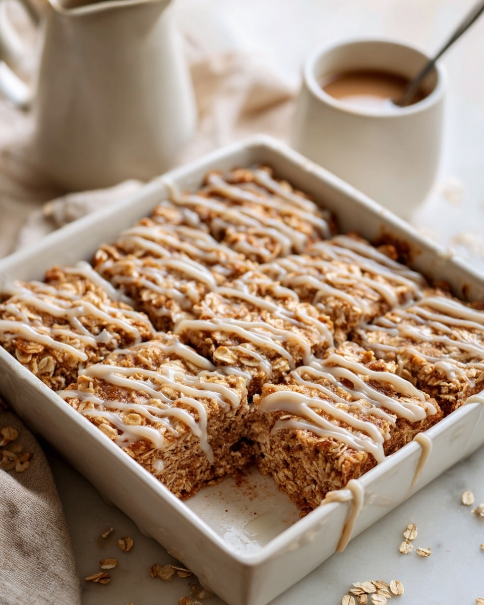 Large white rectangular baking dish filled with a whole batch of freshly baked oatmeal squares generously drizzled with a smooth cinnamon glaze, the top golden brown and textured with oats and warm spices. The dish is set on a white marble countertop with natural lighting, highlighting the rustic yet inviting appearance of the entire uncut dessert, styled like a professional food magazine hero shot. photo taken with an iphone --ar 4:5 --v 7