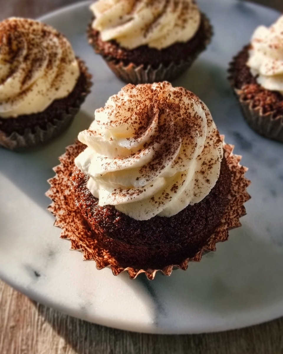 A white rectangular baking tray filled with nine beautifully arranged tiramisu cupcakes, each topped with a generous swirl of creamy mascarpone frosting and a dusting of rich cocoa powder, showcasing the full batch ready to be served, presented on a white marble countertop with natural lighting, captured in a professional food magazine style, photo taken with an iphone --ar 4:5 --v 7