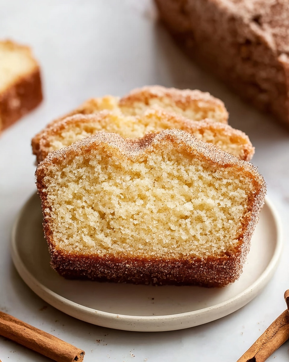 Whole cinnamon sugar coffee cake loaf on a large white plate, showcasing a golden-brown crust dusted evenly with sparkling cinnamon sugar crystals, the top featuring a slightly cracked aromatic cinnamon swirl visible through the sugar topping, all photographed from a professional 3/4 angle on a white marble countertop with natural lighting, styled like a hero food magazine shot, photo taken with an iphone --ar 4:5 --v 7