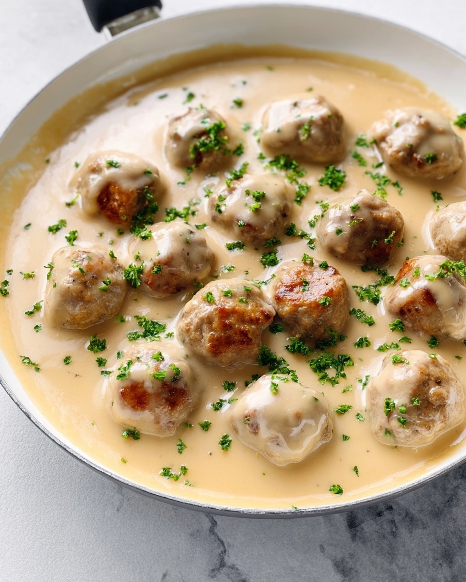 Large white serving bowl filled with a generous portion of Swedish meatballs smothered in creamy, golden gravy, accompanied by a substantial heap of smooth mashed potatoes, garnished with finely chopped fresh parsley, whole dish photographed from a 3/4 angle on a white marble countertop with natural lighting, professional food styling photo taken with an iphone --ar 4:5 --v 7