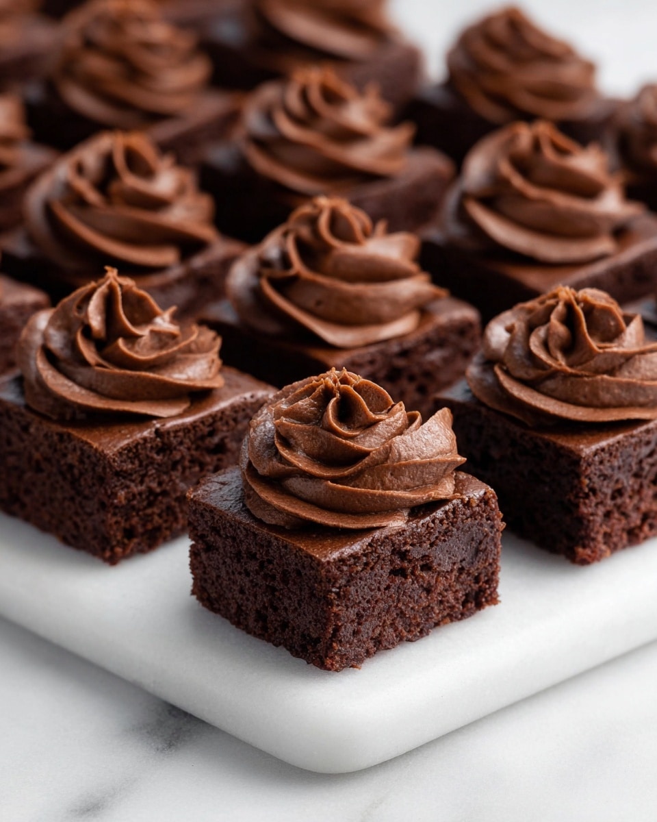 White rectangular platter filled with multiple miniature rich chocolate brownies, each topped with swirls of thick, creamy chocolate frosting, arranged neatly in rows, showcasing the decadence of the full batch, photographed from a 3/4 angle on a white marble countertop with natural lighting, like a hero shot from a food magazine, photo taken with an iphone --ar 4:5 --v 7